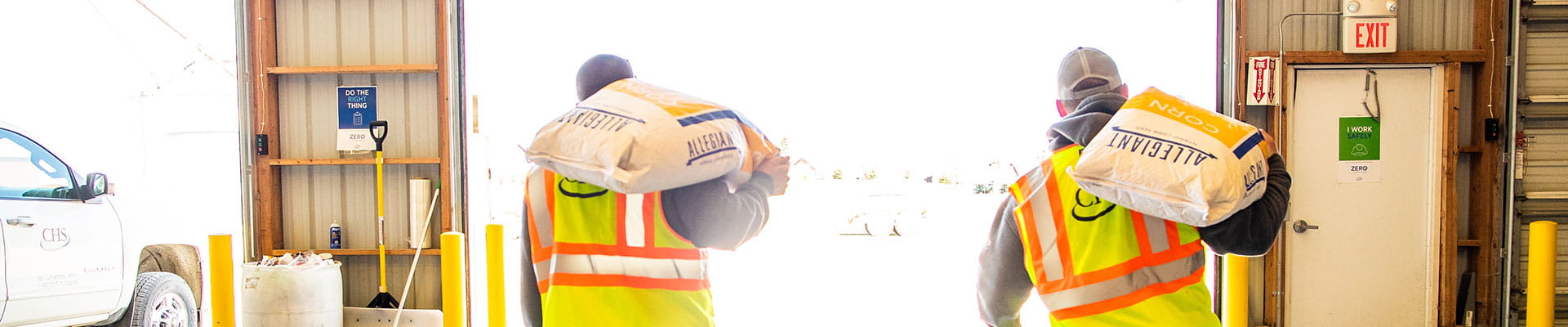Two CHS employees carrying Allegiant Seed corn product bags