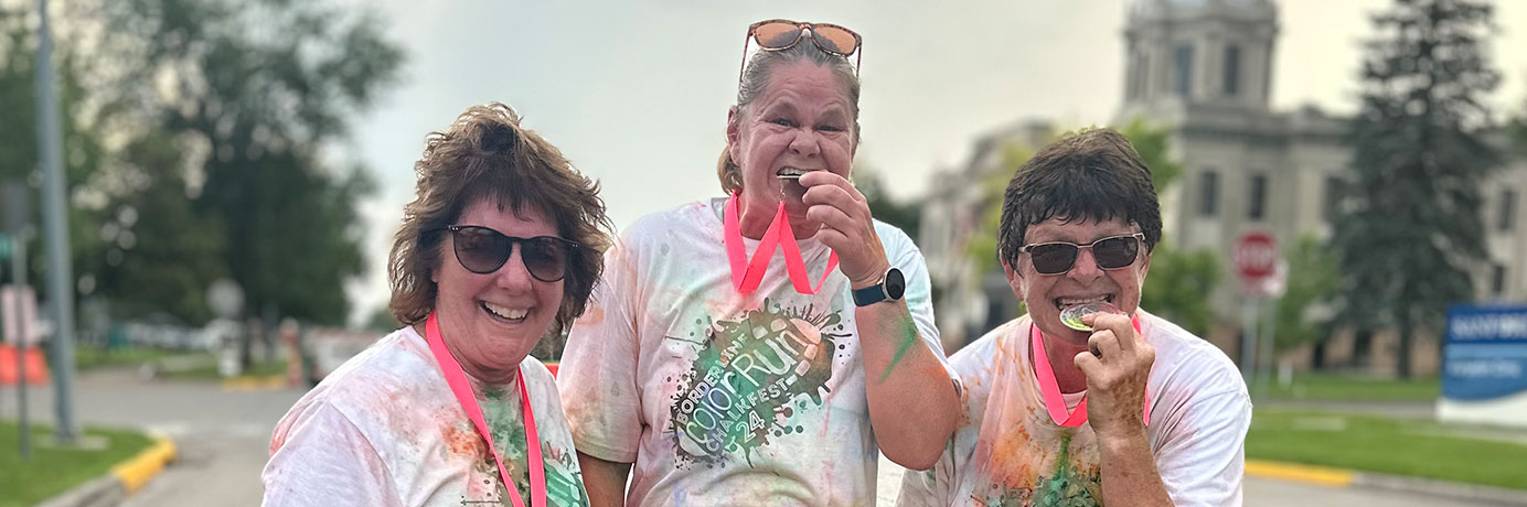 Three borderline color run finishers celebrating with their medals
