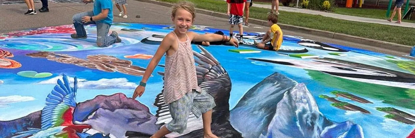 Girl standing on a chalk bird at the Hazen Chalkfest
