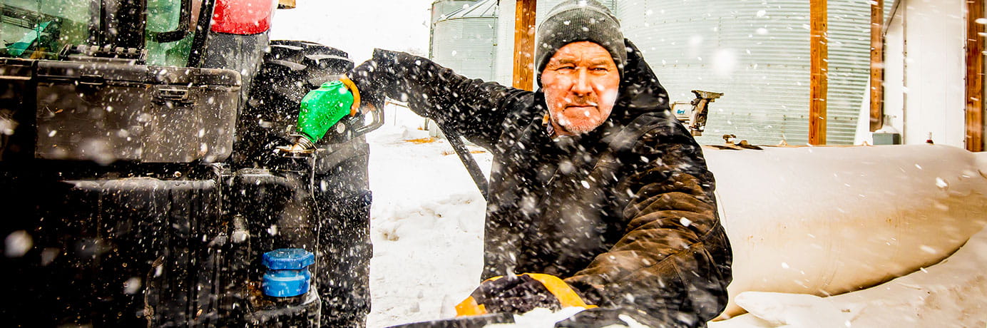 Man filling his tractor's gas tank in the snow
