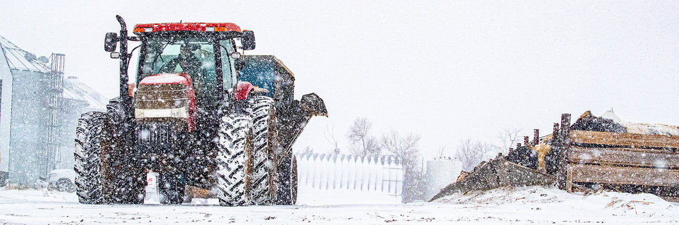 Tractor in the snow in front of a grain bin
