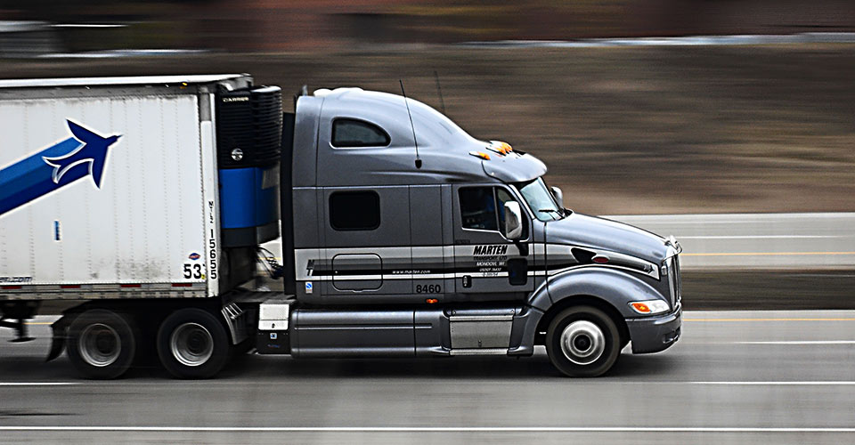 Semi truck driving fast past a blurry background