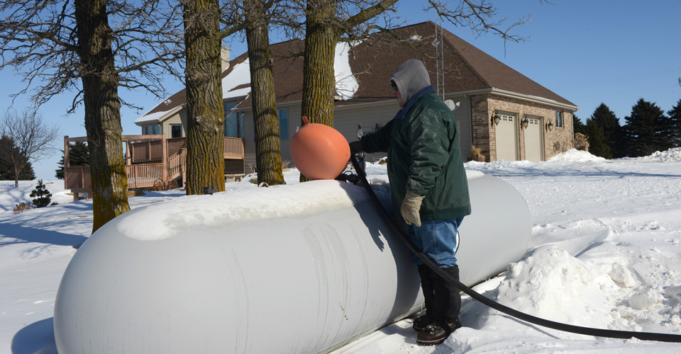 Filling a propane tank behind a house in the winter