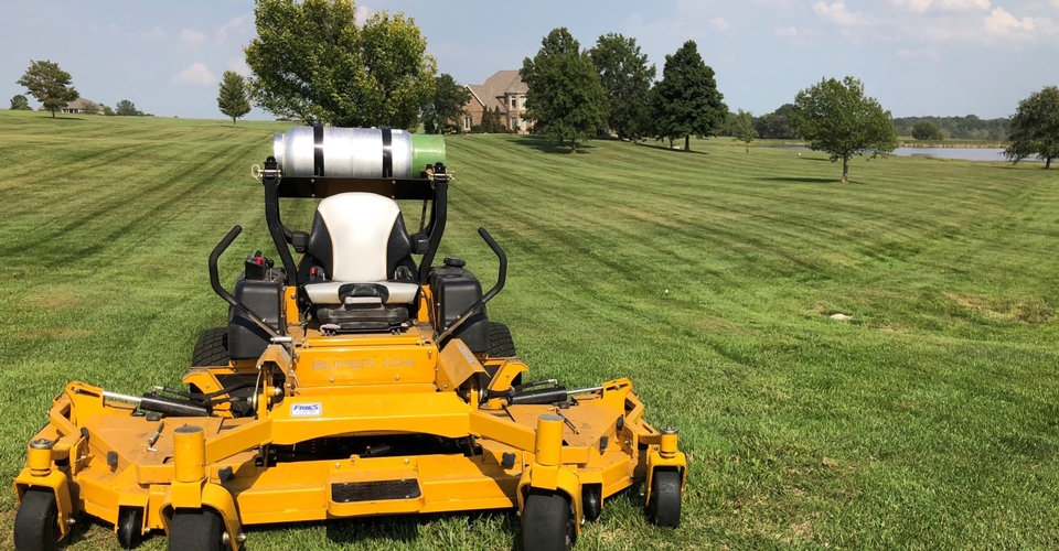 Commercial lawn mower parked in front of straight lines in the grass