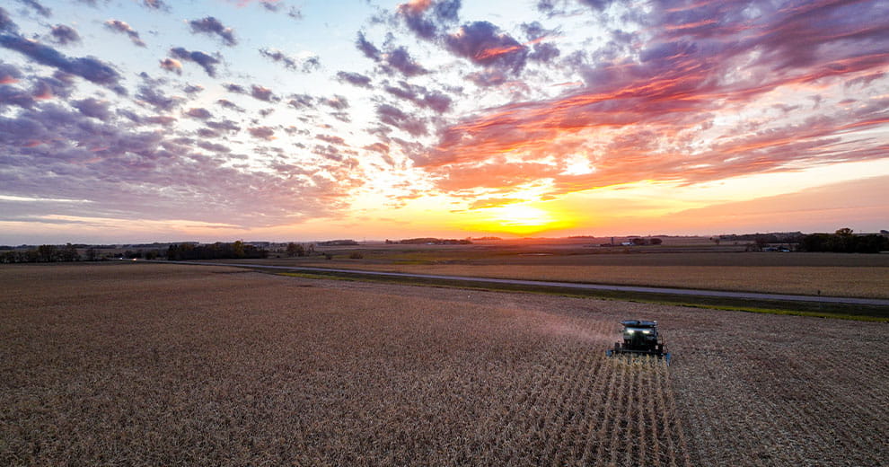 Combine harvesting a field at sunset
