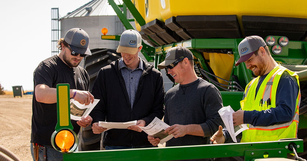 Four men looking at papers.