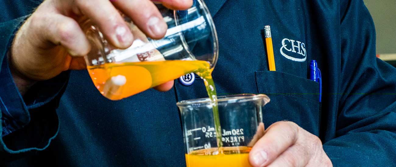 chemist mixing oil in beakers