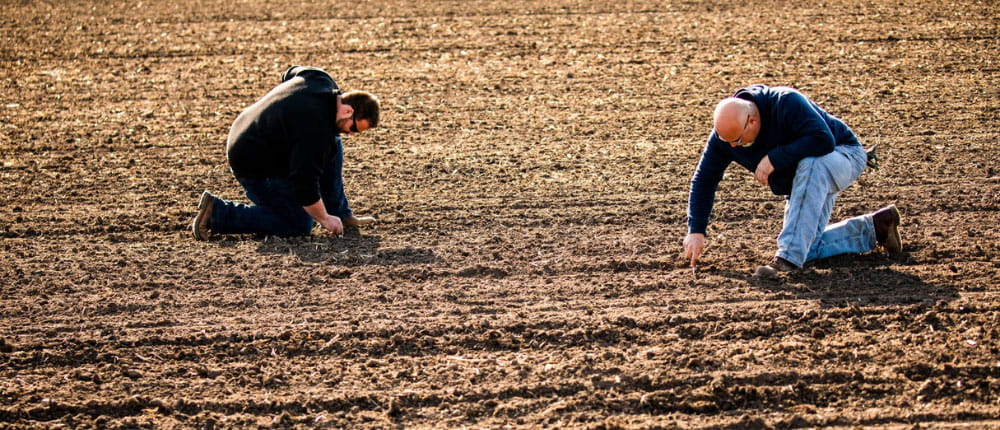 two men soil sampling in a field