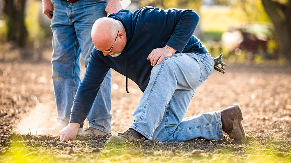 A farmer in a field looking at the ground