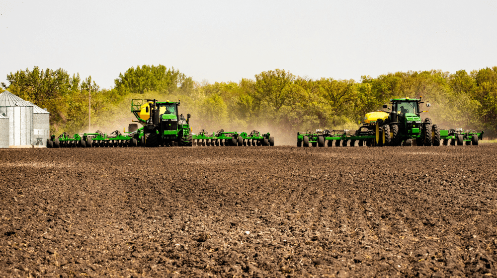 Two tractors planting a crop field