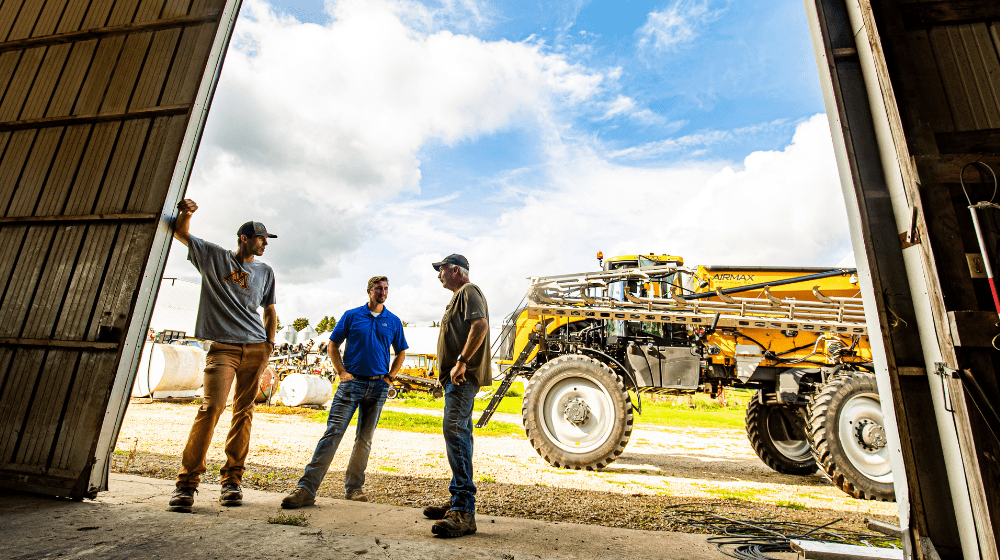 Three men talking in an ag building