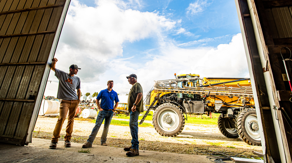 Three men talking in an ag building