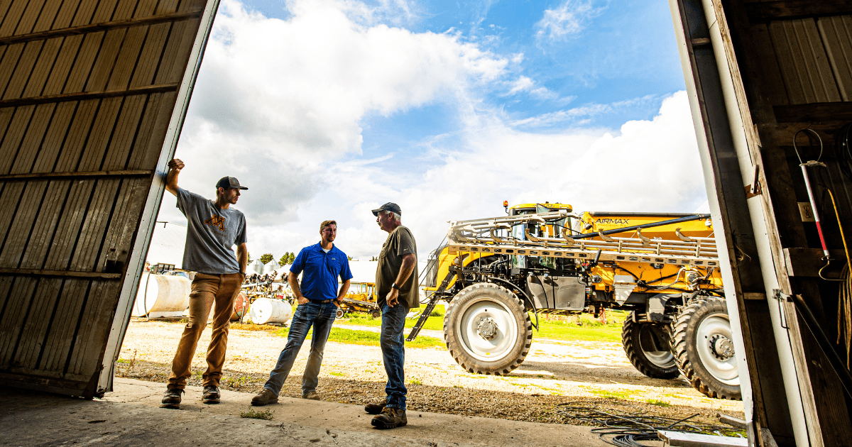 Three men talking in an ag building