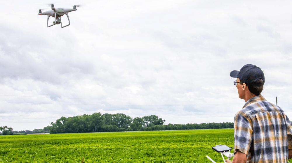 Man flying a drone in a field
