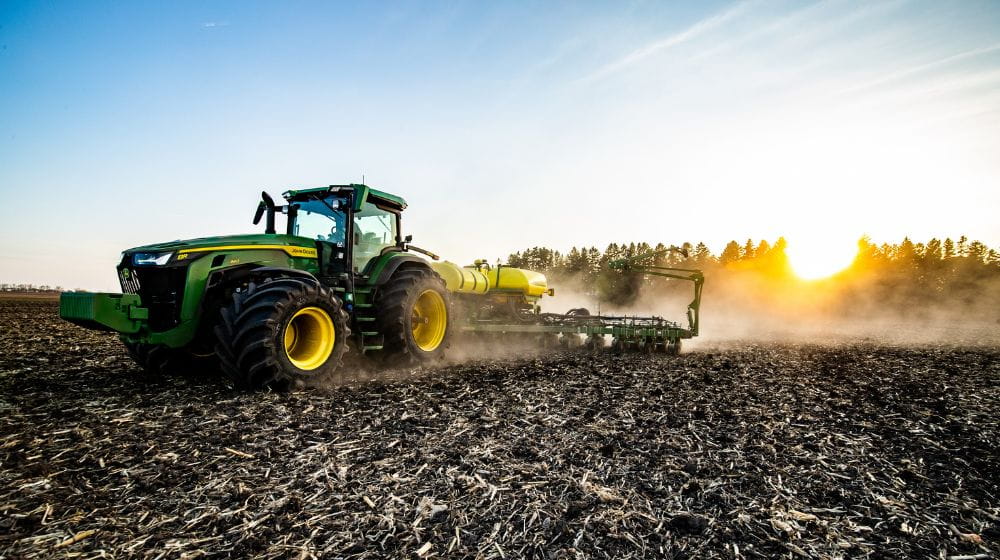A tractor in a field planting. 