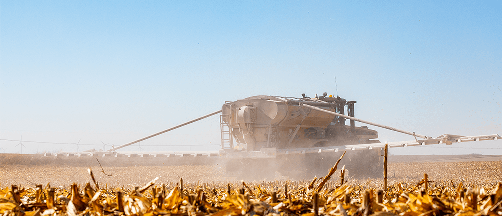 A combine applying fertilizer in a farm field.