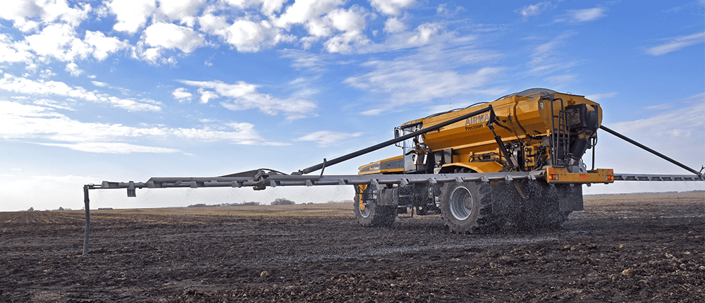A combine applying fertilizer to a field in spring.