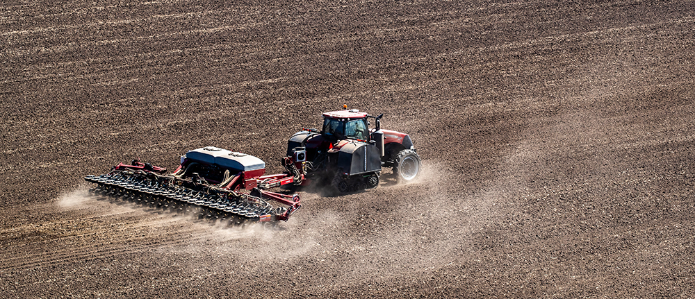 Tractor pulling a row planter across farmland