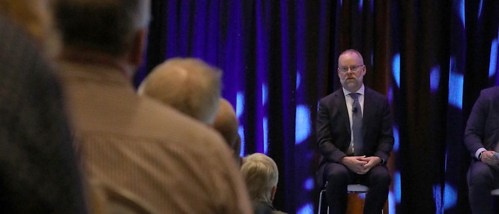Man on stage speaking to an audience