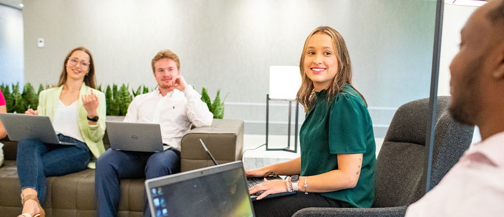 Four interns talking while holding laptops