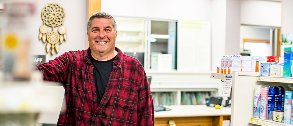 Man standing next to shelves in a pharmacy