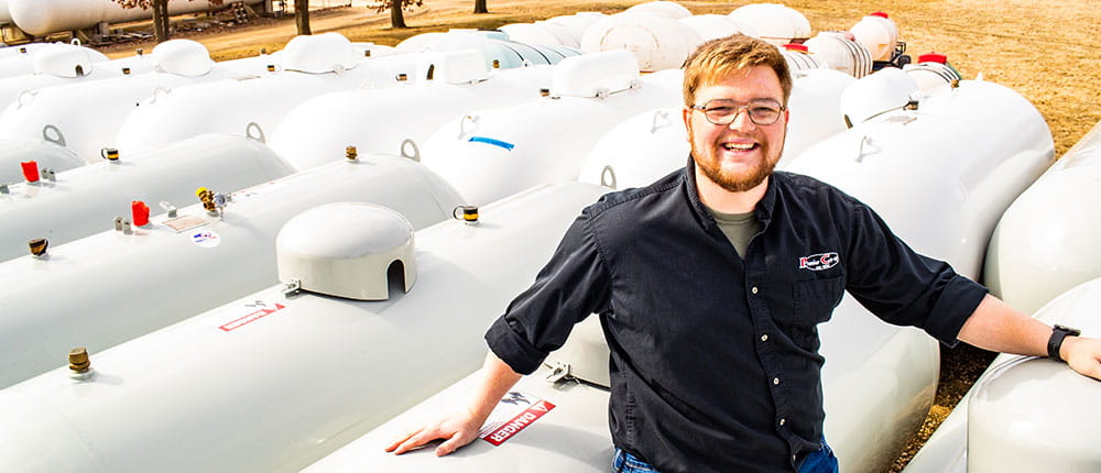Man wearing Premier Cooperative shirt standing next to propane tanks