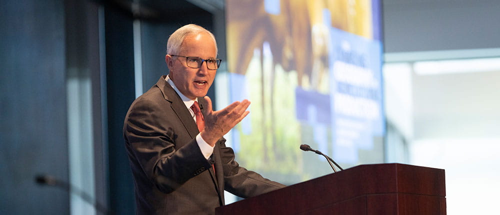 Jay Debertin on stage speaking behind a podium