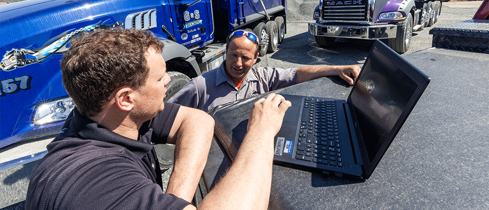 Two men talk by dump trucks