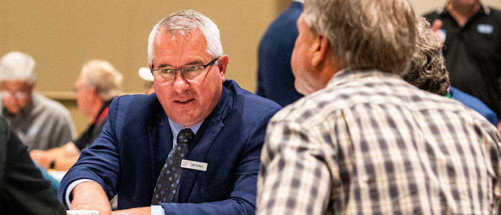 CHS Chair Dan Schurr conversing with others seating around a table.