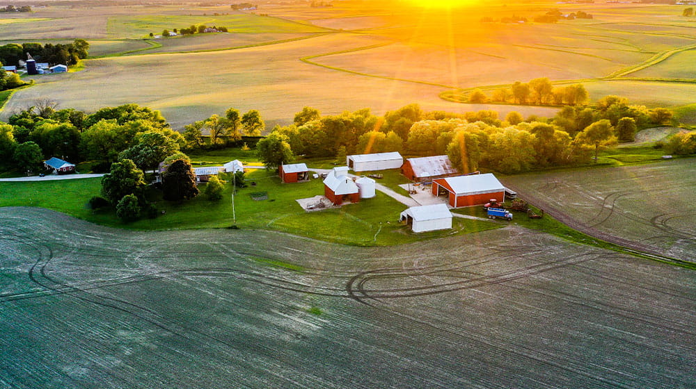 Three photos, depicting two people talking in front of a propane tank, an overhead view of a farm and buildings, and a teacher working with a student inside a greenhouse