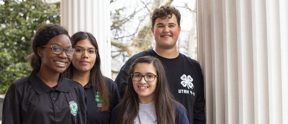 Four young students pose for a photo, smiling.