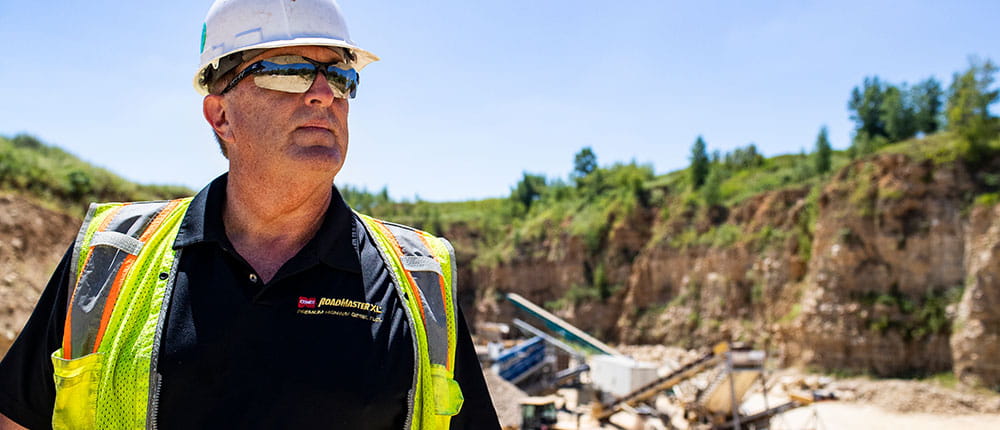 Man in hard hat in front of quarry