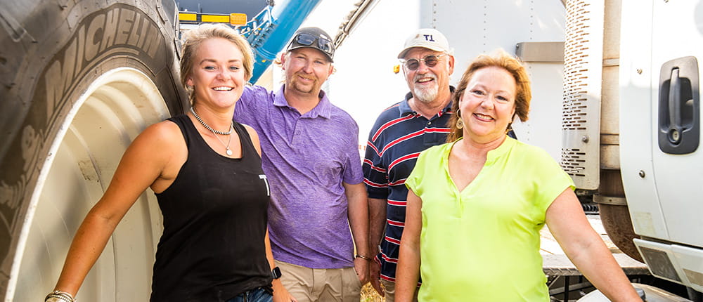 Four family members pose next to farm machinery