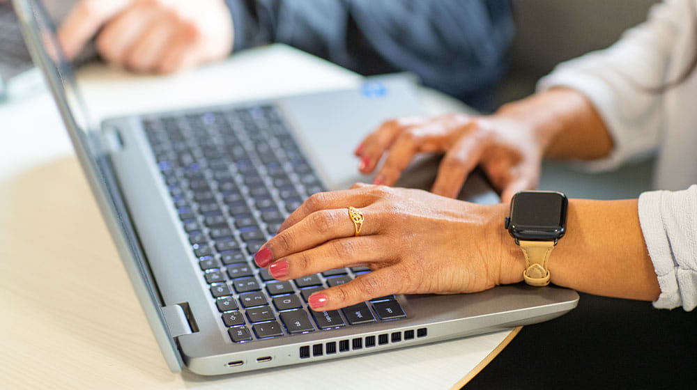 Woman's hands typing on a silver laptop