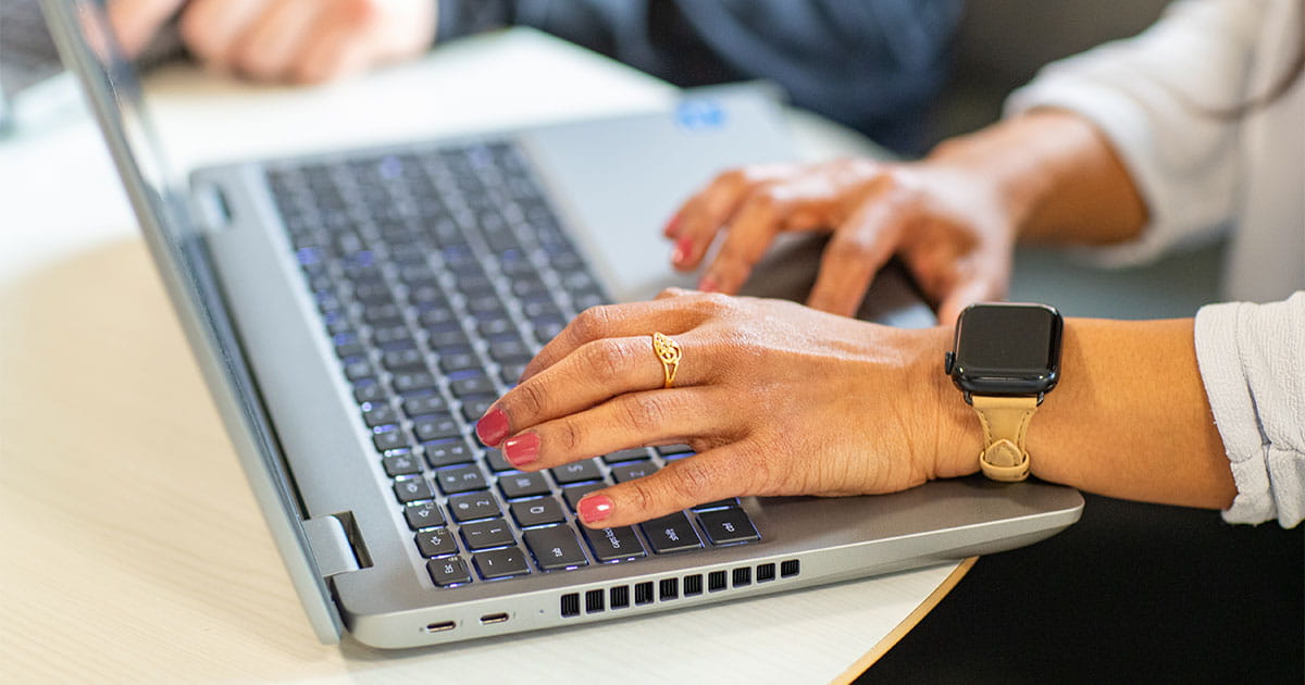 Woman's hands typing on a silver laptop