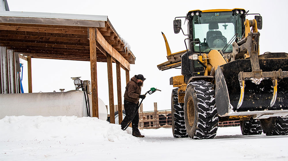 man putting diesel in a tractor during winter