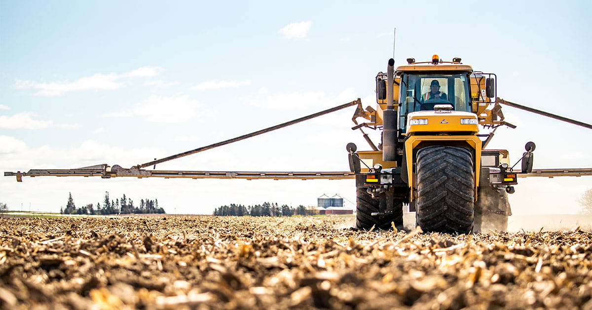 Tractor and sprayer moving through a field