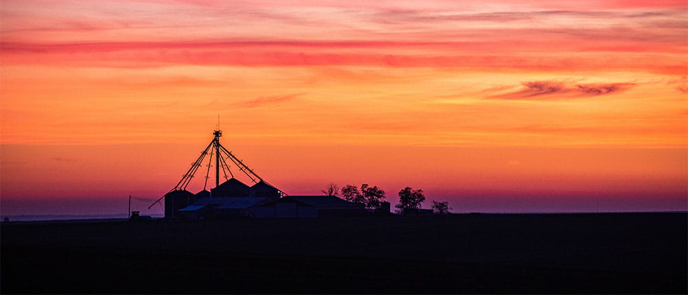 Outline of a grain bin during a sunset
