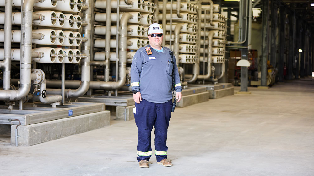 Man wearing safety helmet and gear standing in refinery