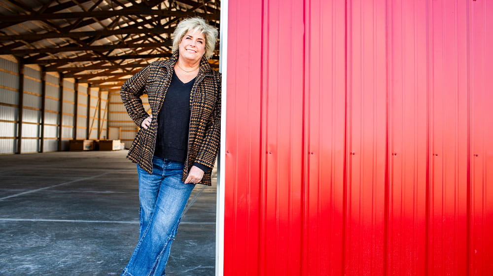 Woman leaning up against red machine shed door