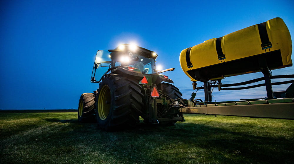 Tractor pulling a fertilizer tank at night