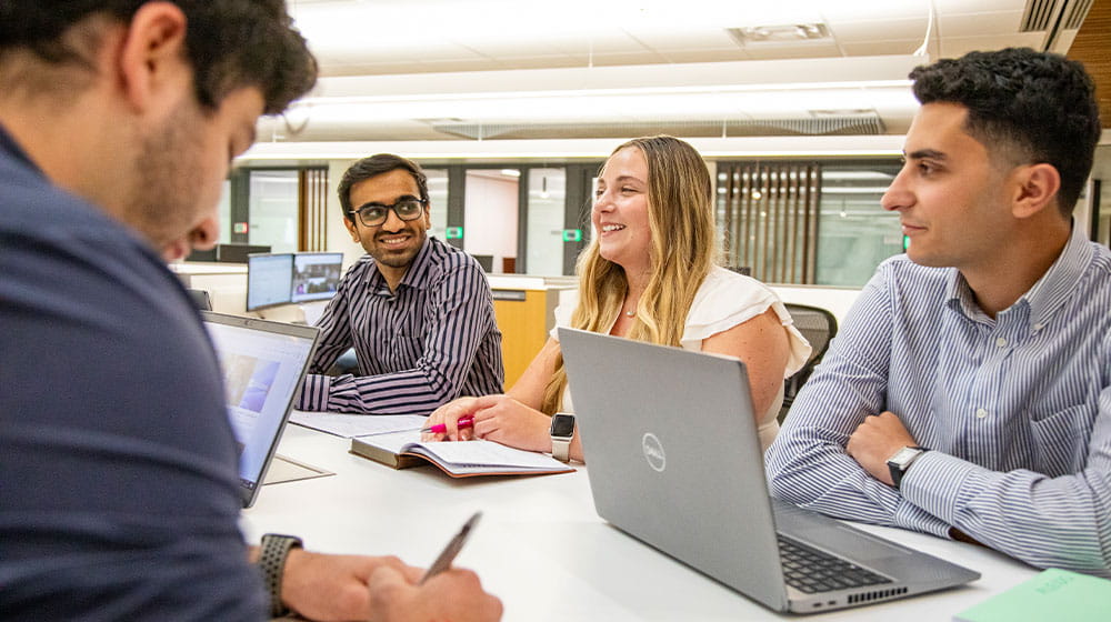 Four interns talking around a table in an office setting