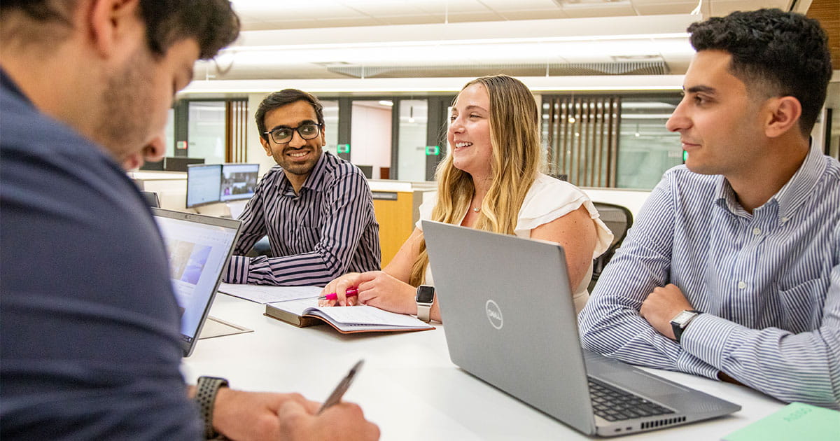 Four interns talking around a table in an office setting