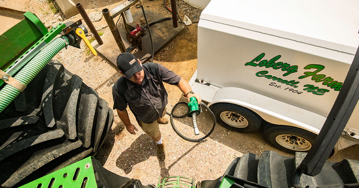 Man holding a fuel hose ready to put diesel fuel in a tractor.