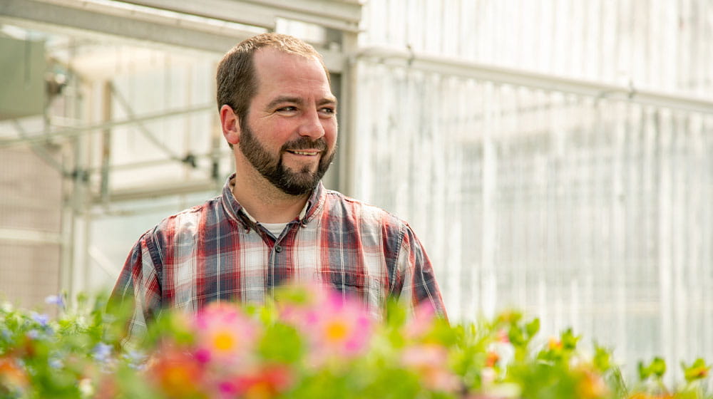 Man standing in a greenhouse with flowers