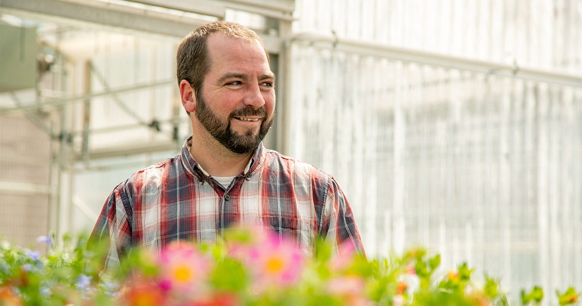 Man standing in a greenhouse with flowers