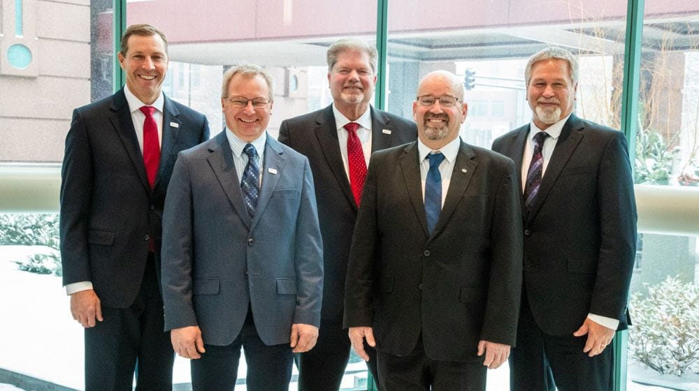 five men standing in suits