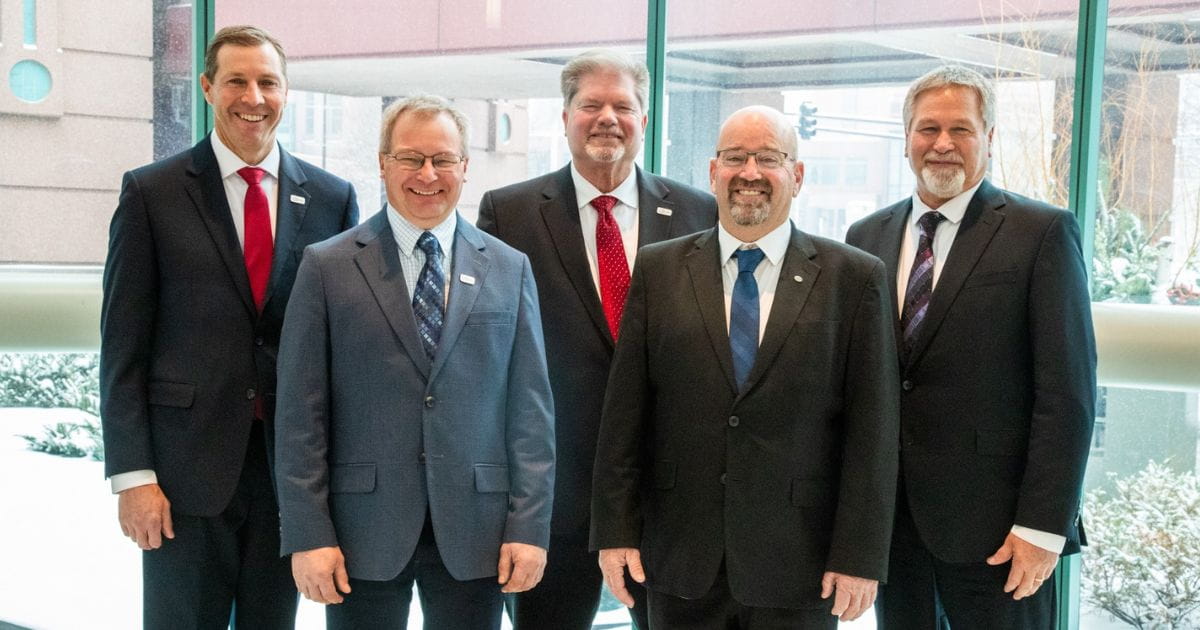 five men standing in suits