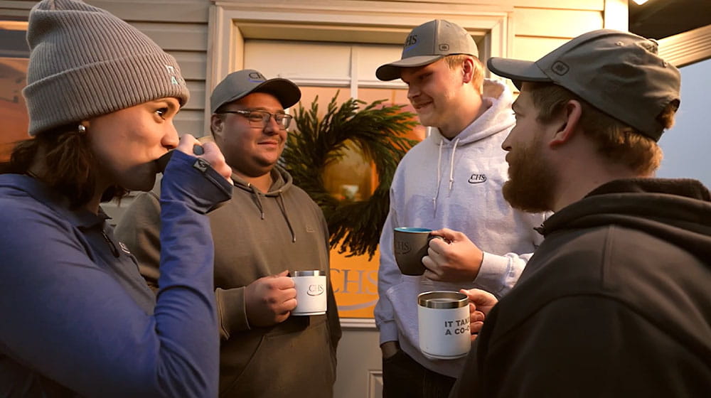 Four people holding mugs near a door. 