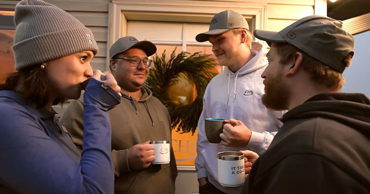 Four people holding mugs near a door. 